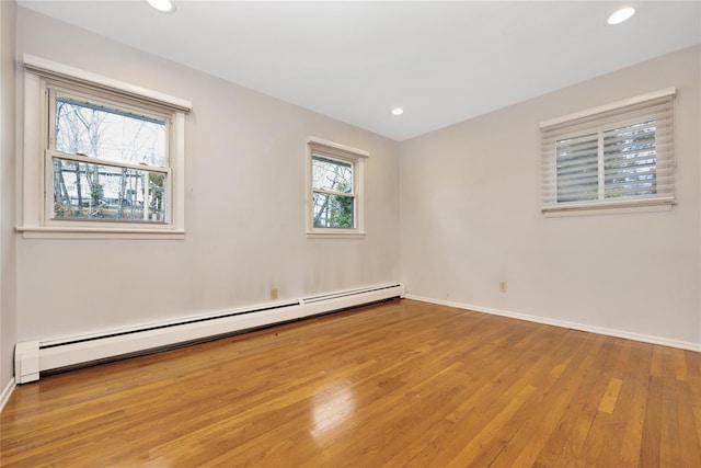 empty room featuring hardwood / wood-style flooring, baseboards, baseboard heating, and recessed lighting