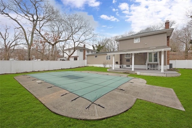 back of house featuring a patio, a fenced backyard, a lawn, a fenced in pool, and a chimney