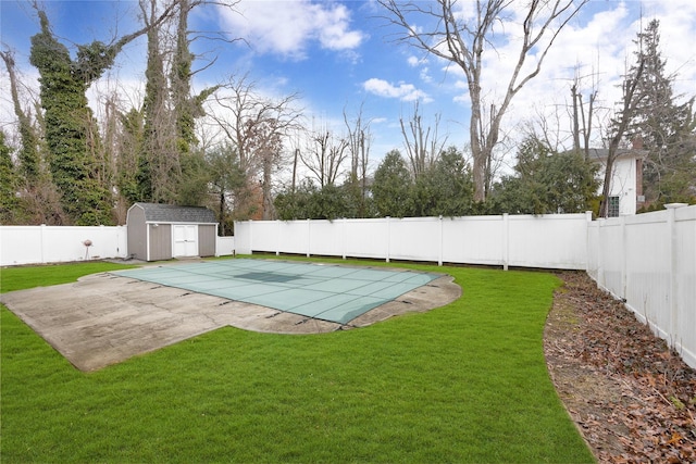 view of pool with a fenced backyard, an outdoor structure, a yard, a fenced in pool, and a storage unit