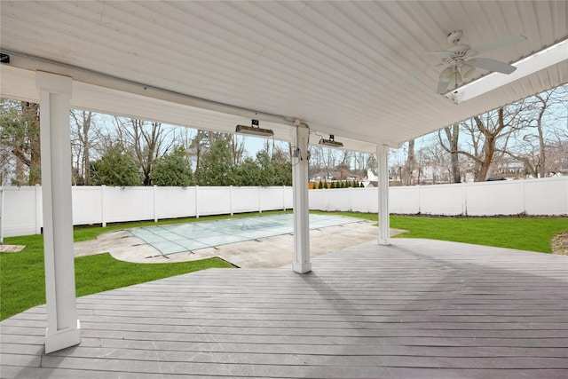 deck featuring a ceiling fan, a fenced backyard, and a yard