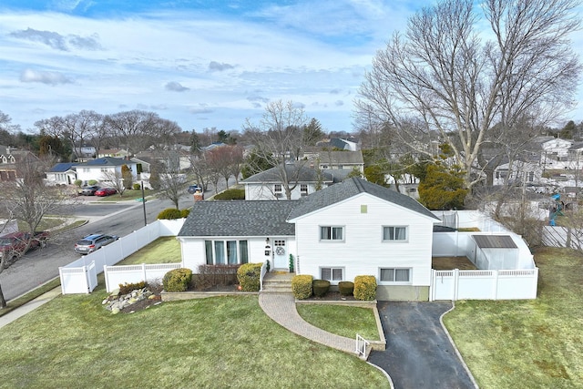 exterior space with driveway, a fenced front yard, a front yard, and a residential view