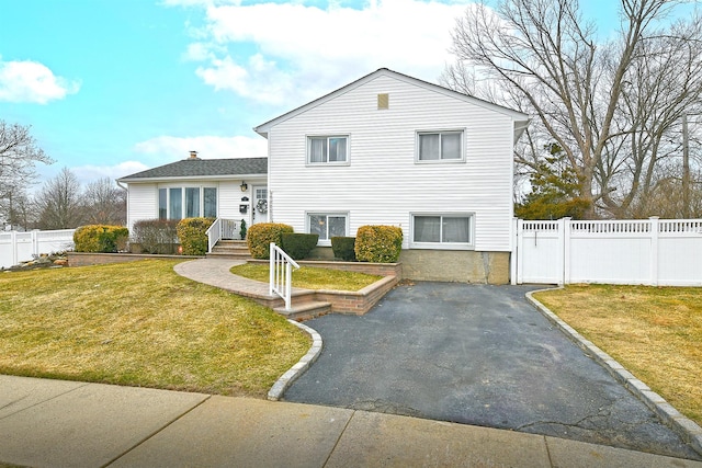 tri-level home featuring a front lawn and fence