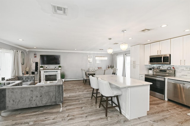 kitchen featuring light wood finished floors, visible vents, white cabinets, a center island, and stainless steel appliances