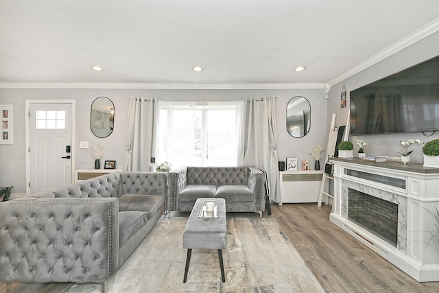 living room with recessed lighting, crown molding, a premium fireplace, and wood finished floors