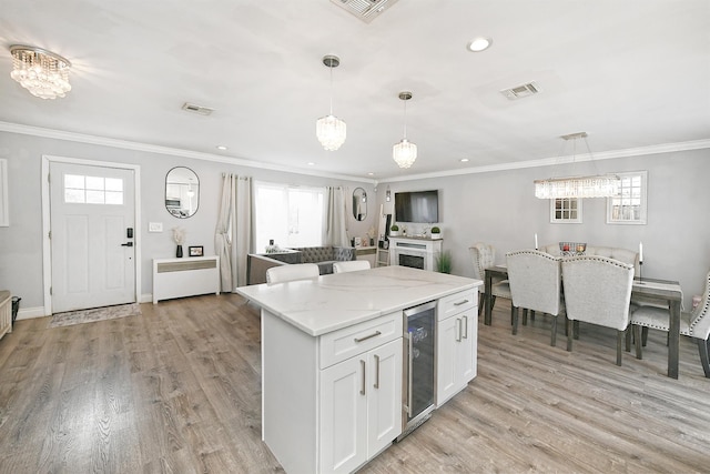 kitchen featuring light wood-style floors, beverage cooler, visible vents, and crown molding