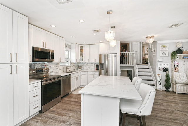 kitchen featuring visible vents, appliances with stainless steel finishes, a kitchen breakfast bar, a center island, and a sink