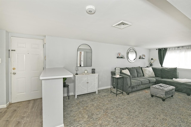 living room featuring visible vents, baseboards, and wood finished floors