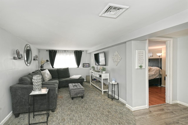 living area with wood finished floors, visible vents, and baseboards