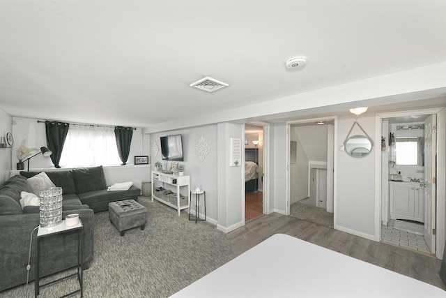 living room featuring baseboards, visible vents, and wood finished floors