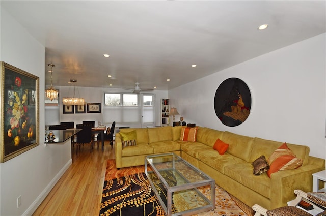 living area with baseboards, ceiling fan with notable chandelier, wood finished floors, and recessed lighting