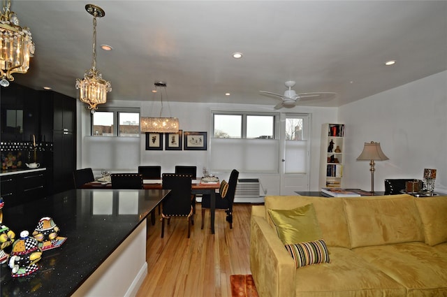 living area with recessed lighting, light wood finished floors, and ceiling fan with notable chandelier