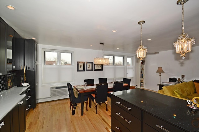 kitchen featuring light wood-style floors, recessed lighting, a wall unit AC, and hanging light fixtures