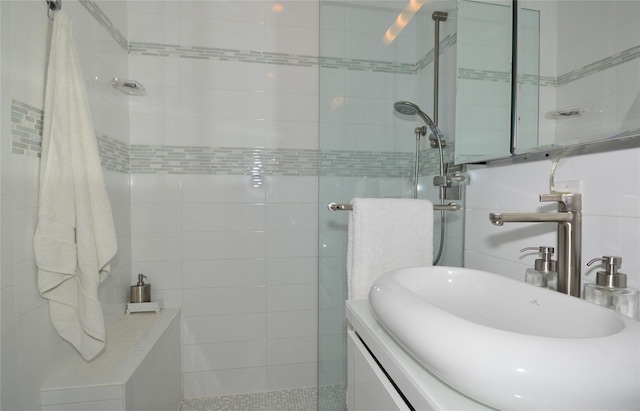 bathroom with a shower stall, tile walls, and a sink