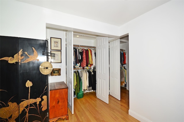 bedroom with light wood-type flooring, baseboards, and a closet