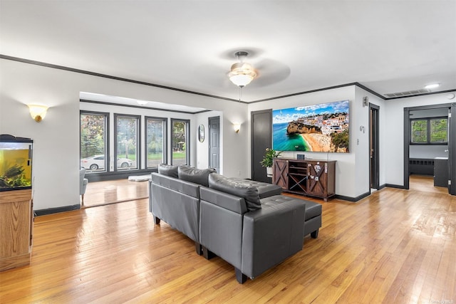 living room featuring light wood-style floors, ornamental molding, and baseboards