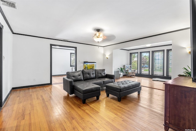 living room with ceiling fan, visible vents, baseboards, light wood-style floors, and ornamental molding