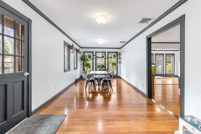 dining area with light wood-style floors, visible vents, crown molding, and baseboards