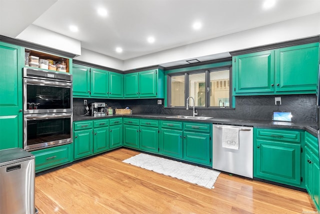 kitchen with appliances with stainless steel finishes, dark countertops, a sink, and light wood-style flooring