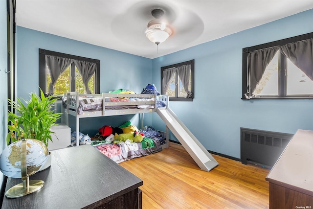 bedroom with ceiling fan, radiator heating unit, wood finished floors, and baseboards