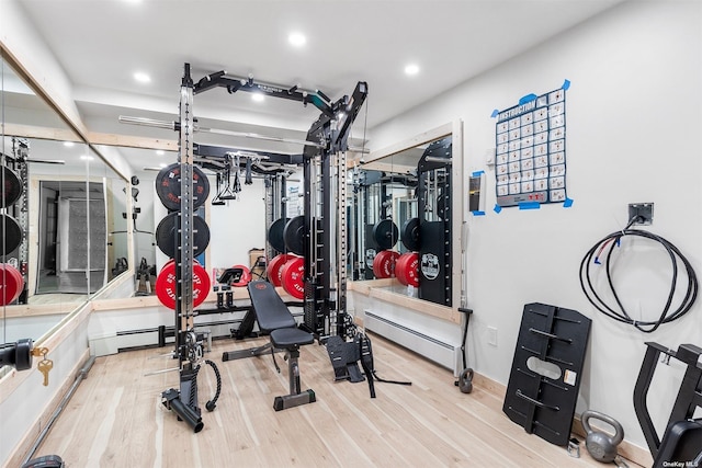 workout room with a baseboard heating unit, wood finished floors, and recessed lighting