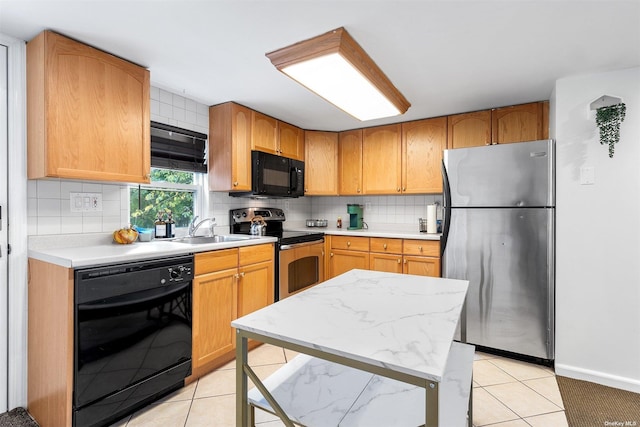 kitchen featuring decorative backsplash, light countertops, black appliances, a sink, and light tile patterned flooring