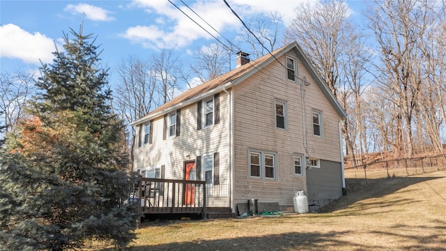 view of side of home featuring a lawn, a chimney, a wooden deck, and fence