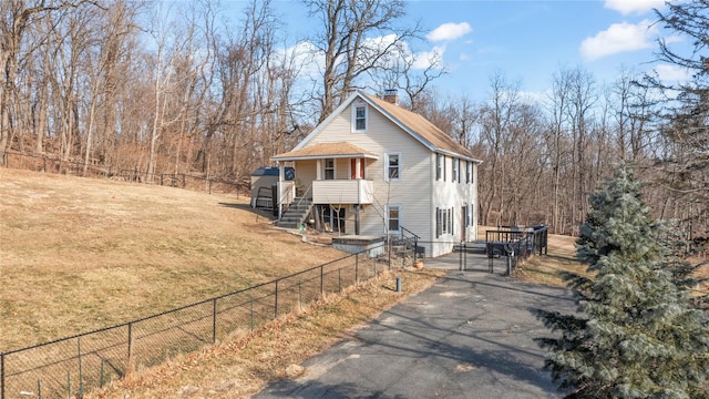 view of front of property with a front lawn, a fenced front yard, a chimney, and aphalt driveway