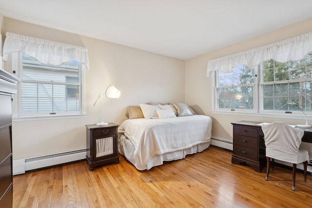 bedroom with light wood finished floors and baseboard heating