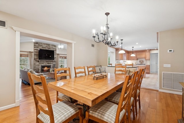 dining area featuring baseboards, visible vents, a fireplace, and light wood finished floors