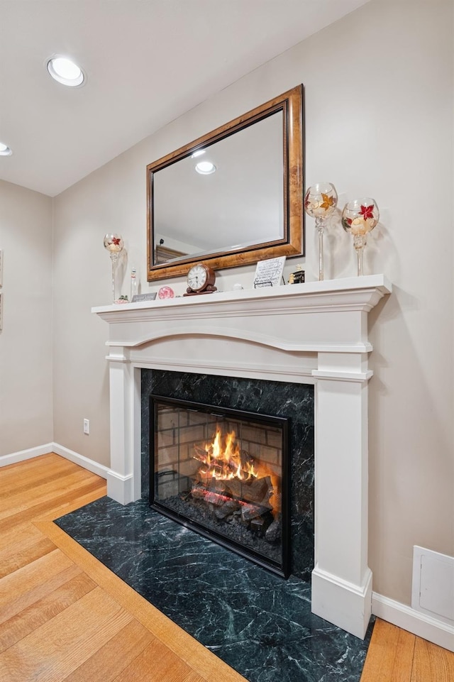 interior details featuring wood finished floors, a high end fireplace, and baseboards