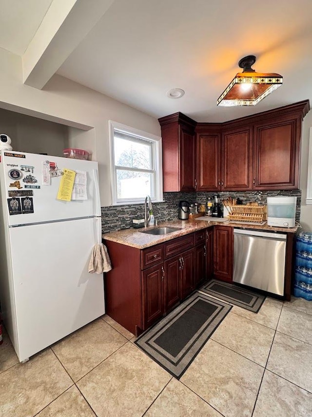 kitchen featuring light tile patterned floors, backsplash, freestanding refrigerator, a sink, and dishwasher