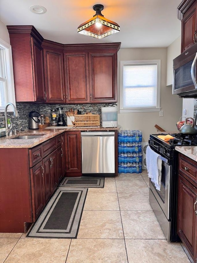 kitchen featuring appliances with stainless steel finishes, a sink, decorative backsplash, and light tile patterned floors