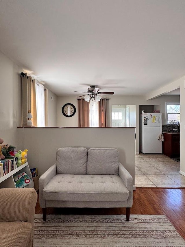 living room with ceiling fan, light wood-style flooring, and a wealth of natural light