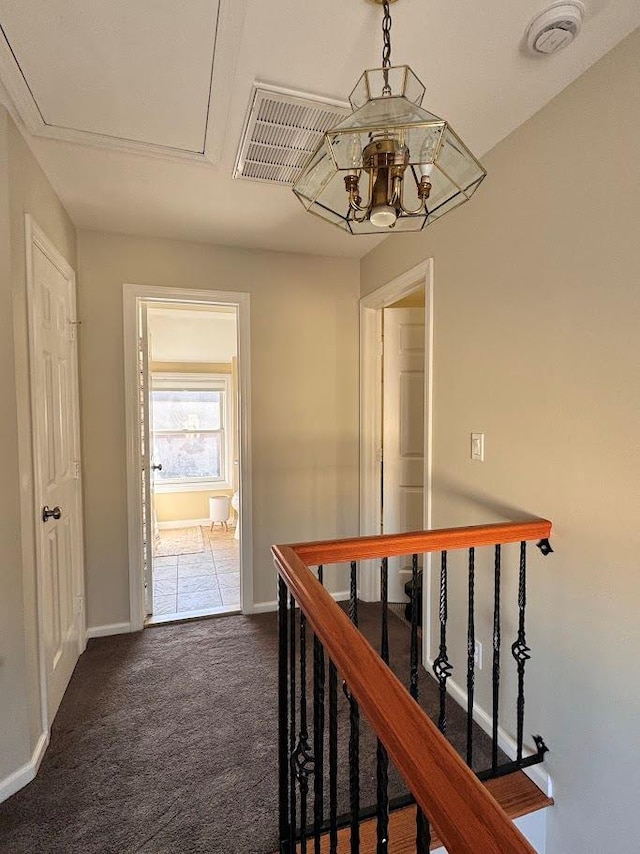 hall with visible vents, dark carpet, an upstairs landing, a chandelier, and baseboards