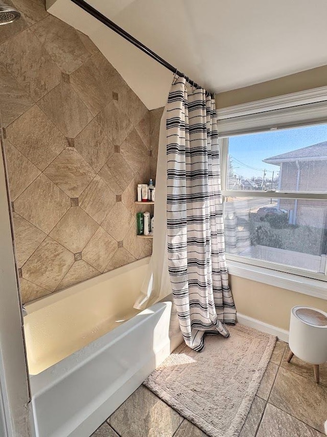 bathroom with baseboards and shower / bath combination with curtain