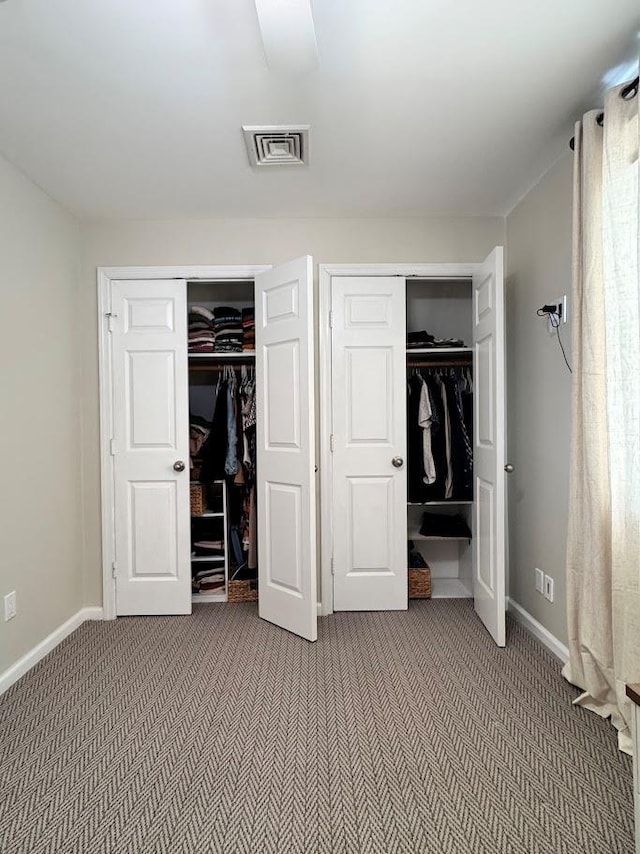 unfurnished bedroom with carpet floors, baseboards, visible vents, and multiple closets