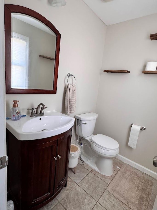 bathroom with toilet, tile patterned flooring, baseboards, and vanity