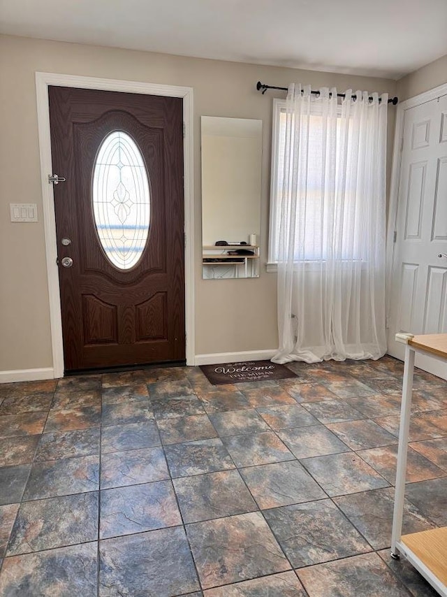 entrance foyer featuring stone finish floor and baseboards