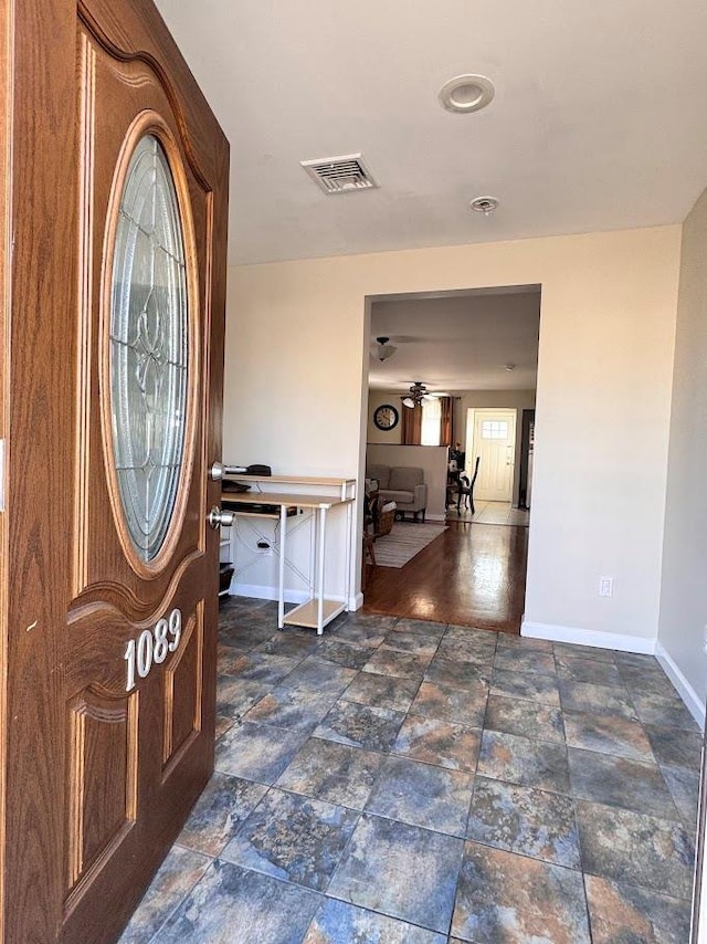 foyer with stone finish floor, visible vents, ceiling fan, and baseboards