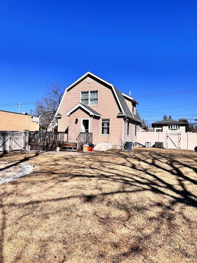 back of house with a yard, a gate, a gambrel roof, and fence