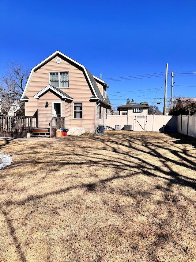 view of side of property with a gate, fence, and a gambrel roof