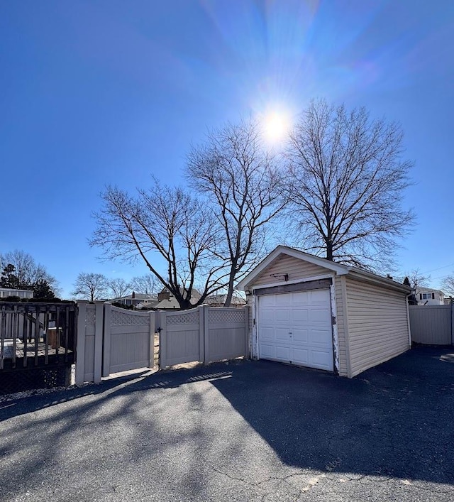 detached garage with a gate, fence, and aphalt driveway