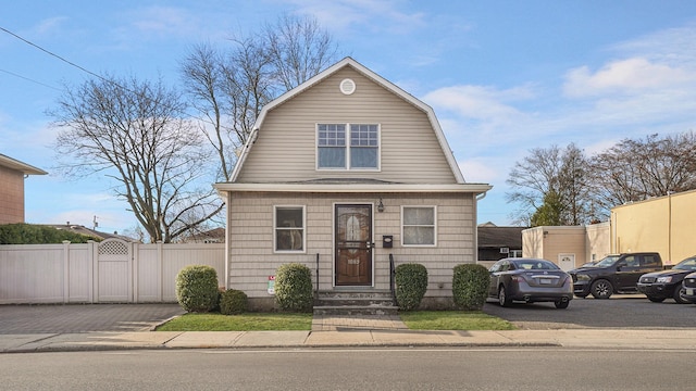 dutch colonial with a gambrel roof, fence, and a gate