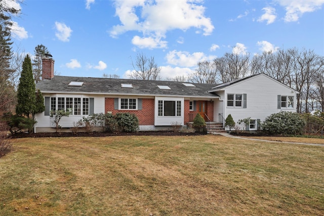 view of front of house with a chimney, a front lawn, and brick siding