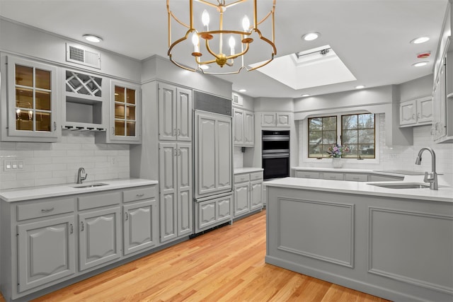 kitchen with double oven, gray cabinets, and a sink