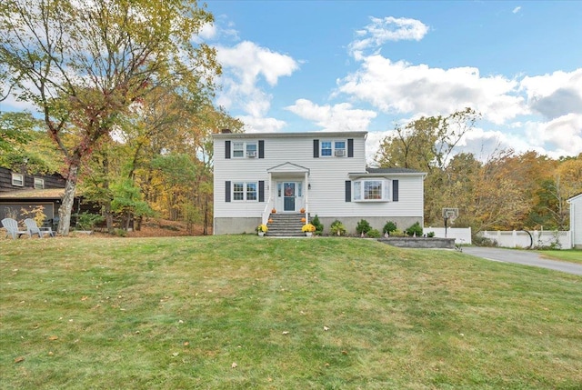 colonial inspired home featuring a front yard and fence