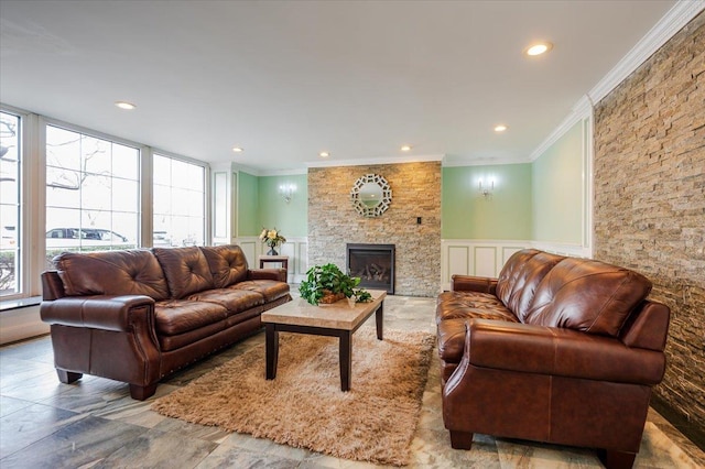 living room with a large fireplace, ornamental molding, a decorative wall, and wainscoting