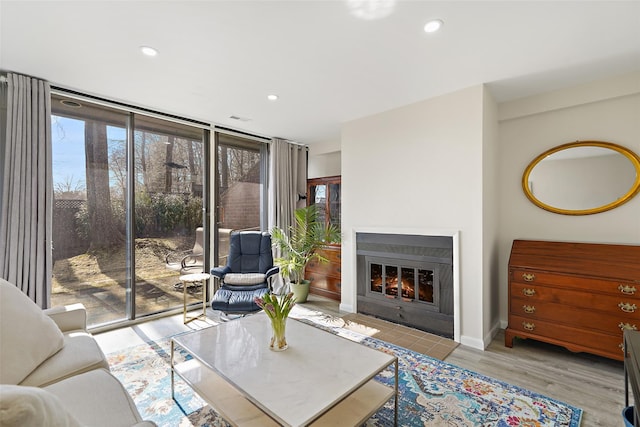 living room featuring recessed lighting, floor to ceiling windows, a tiled fireplace, and wood finished floors