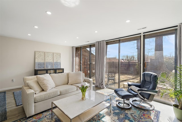 living area featuring a wall of windows, recessed lighting, visible vents, and baseboards