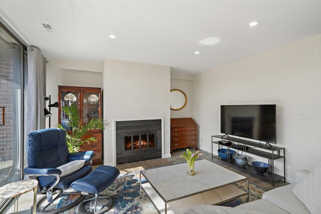 living room with recessed lighting, wood finished floors, visible vents, baseboards, and a glass covered fireplace